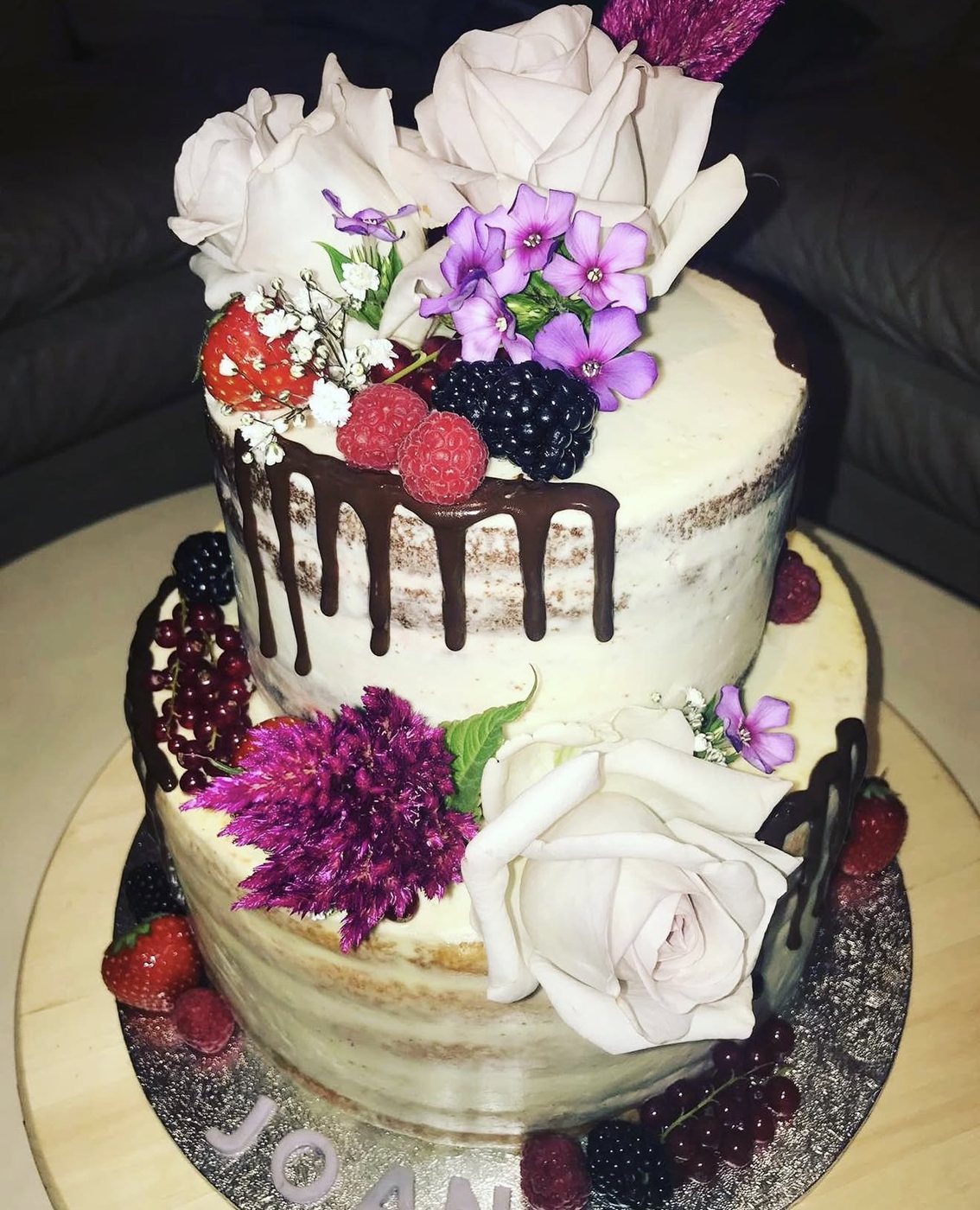 Tweelaagse naked cake met verse bloemen en rood fruit