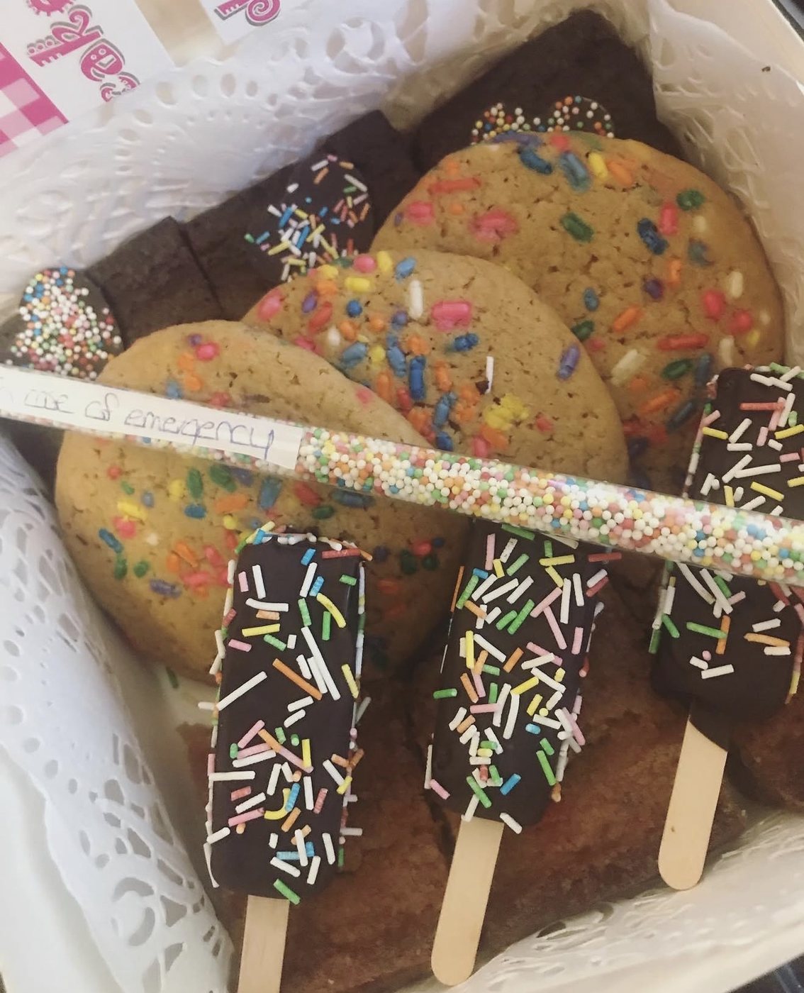Mand met koekjes, brownies en cakejes op een stokje