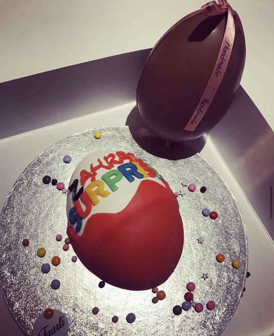 Taart in de vorm van een groot verrassingsei met een chocolade-ei ernaast